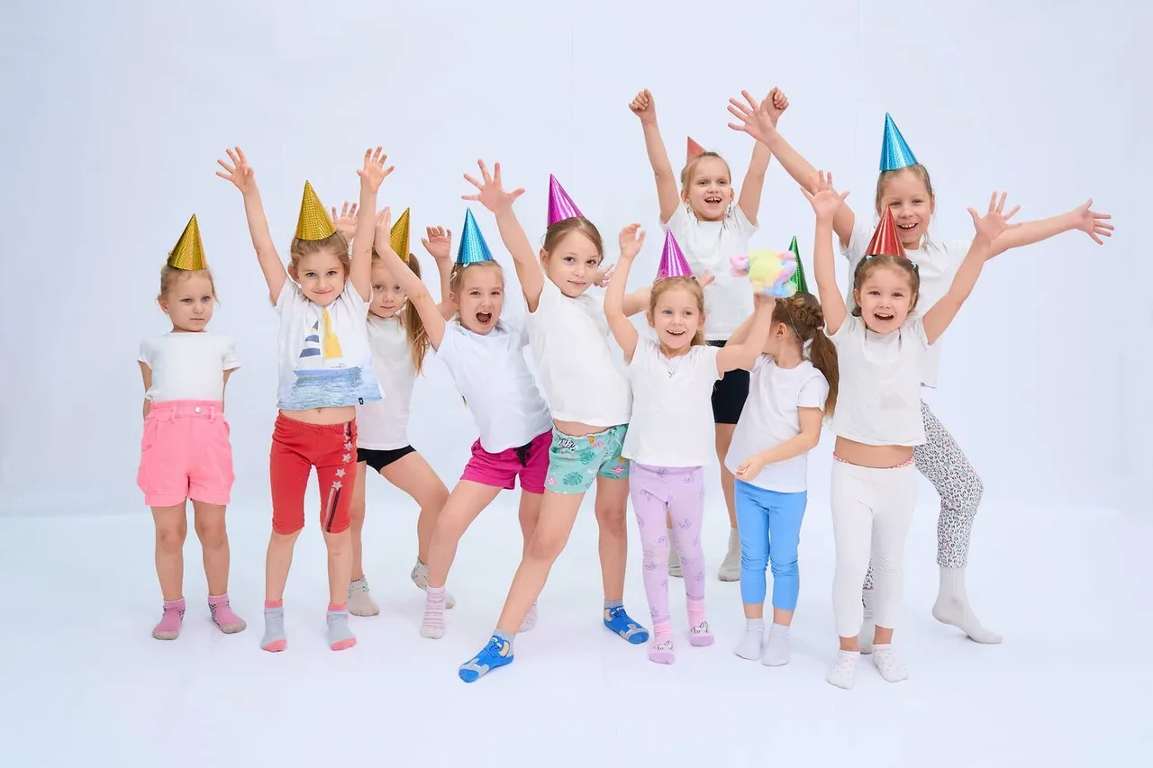 Дети в праздничных колпачках стоят вместе в студии Kids Point
